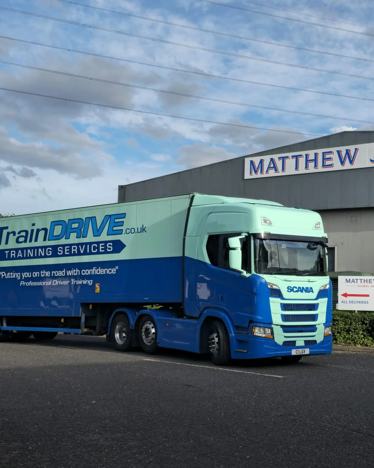 A blue truck parked in front of a train drive building.