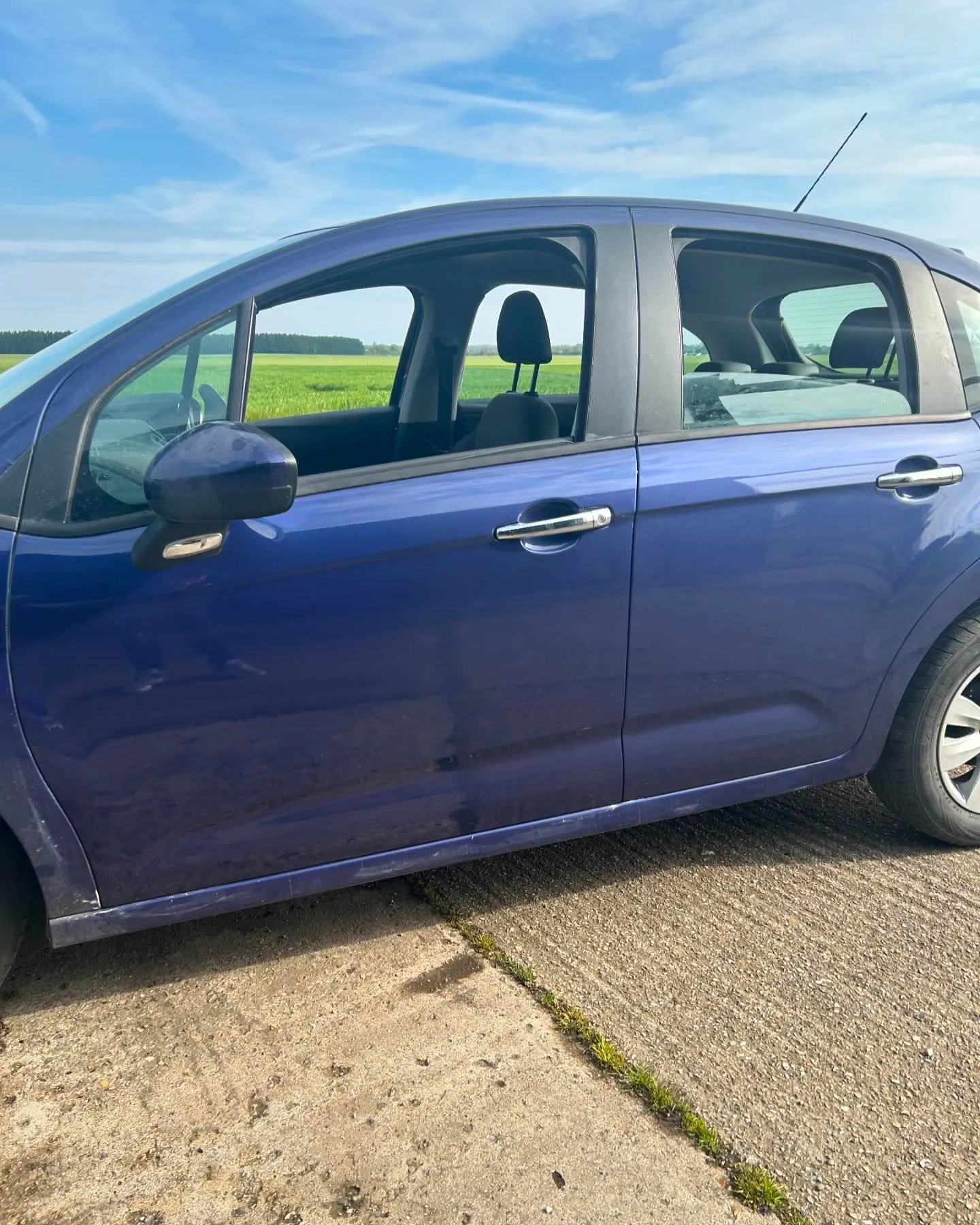 A blue car parked on the side of a road.