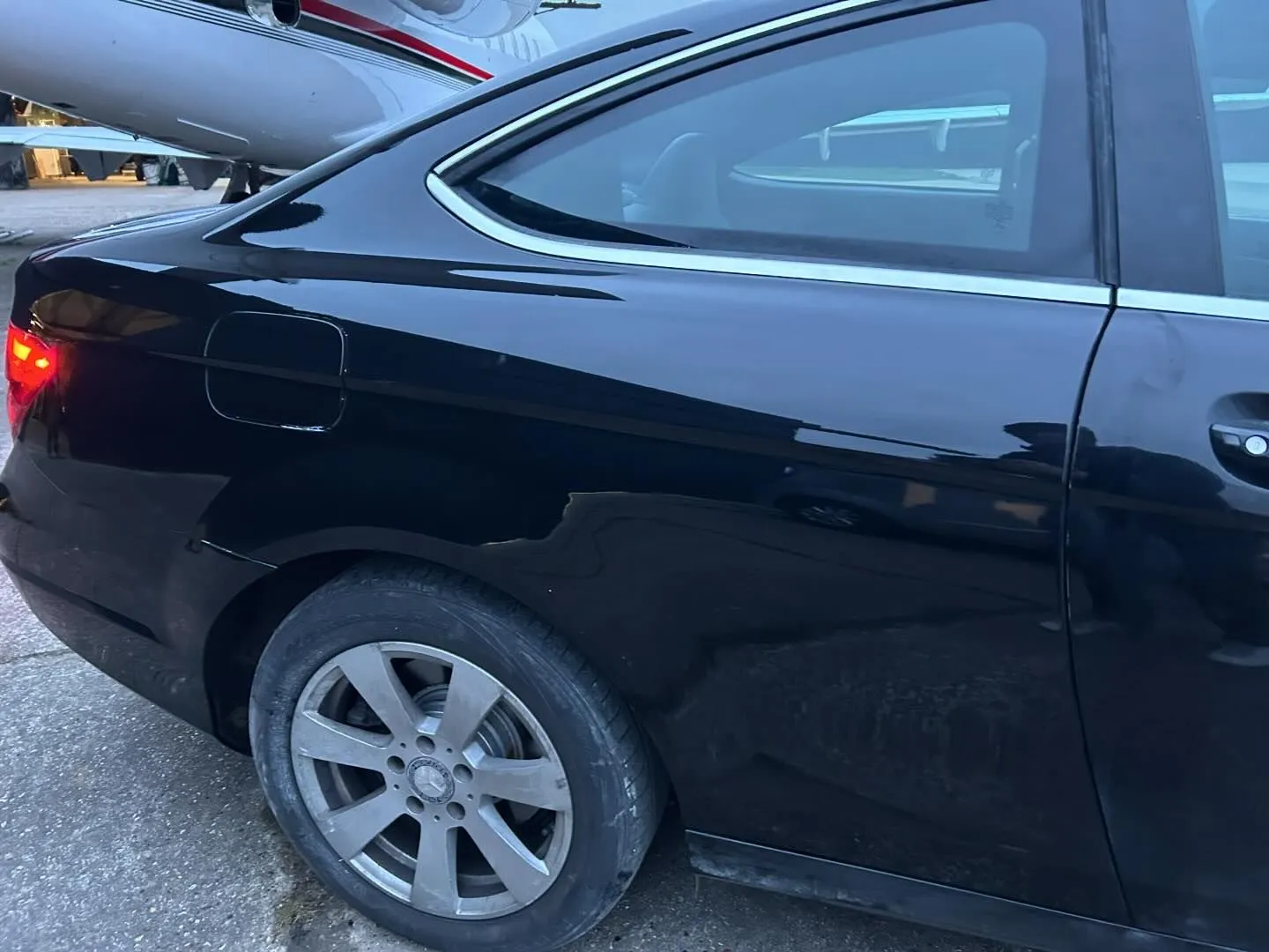 A black car parked next to a jetliner.