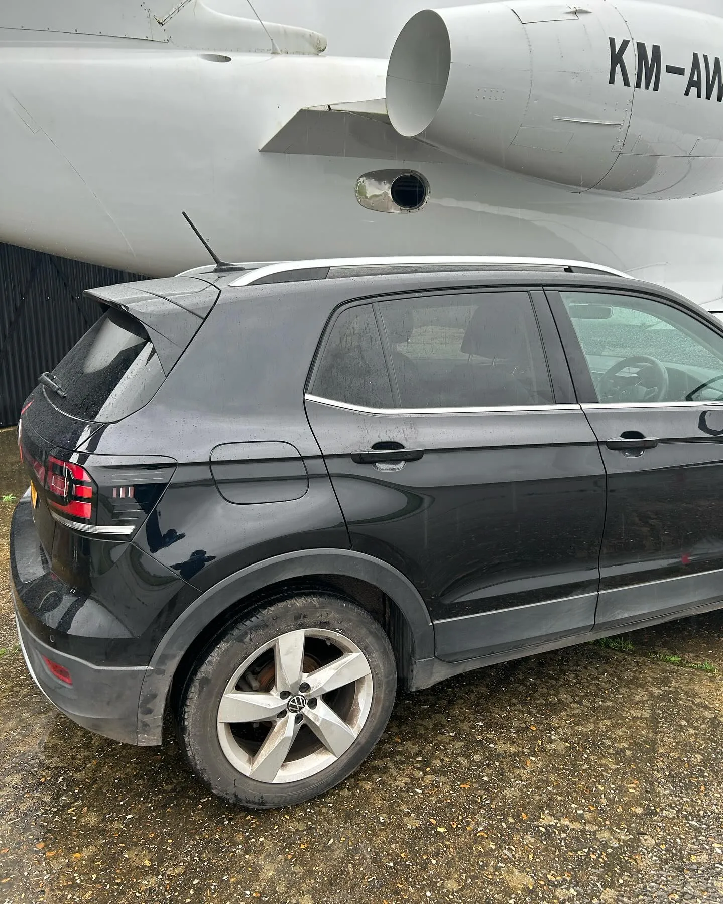 A black suv parked in front of an airplane.