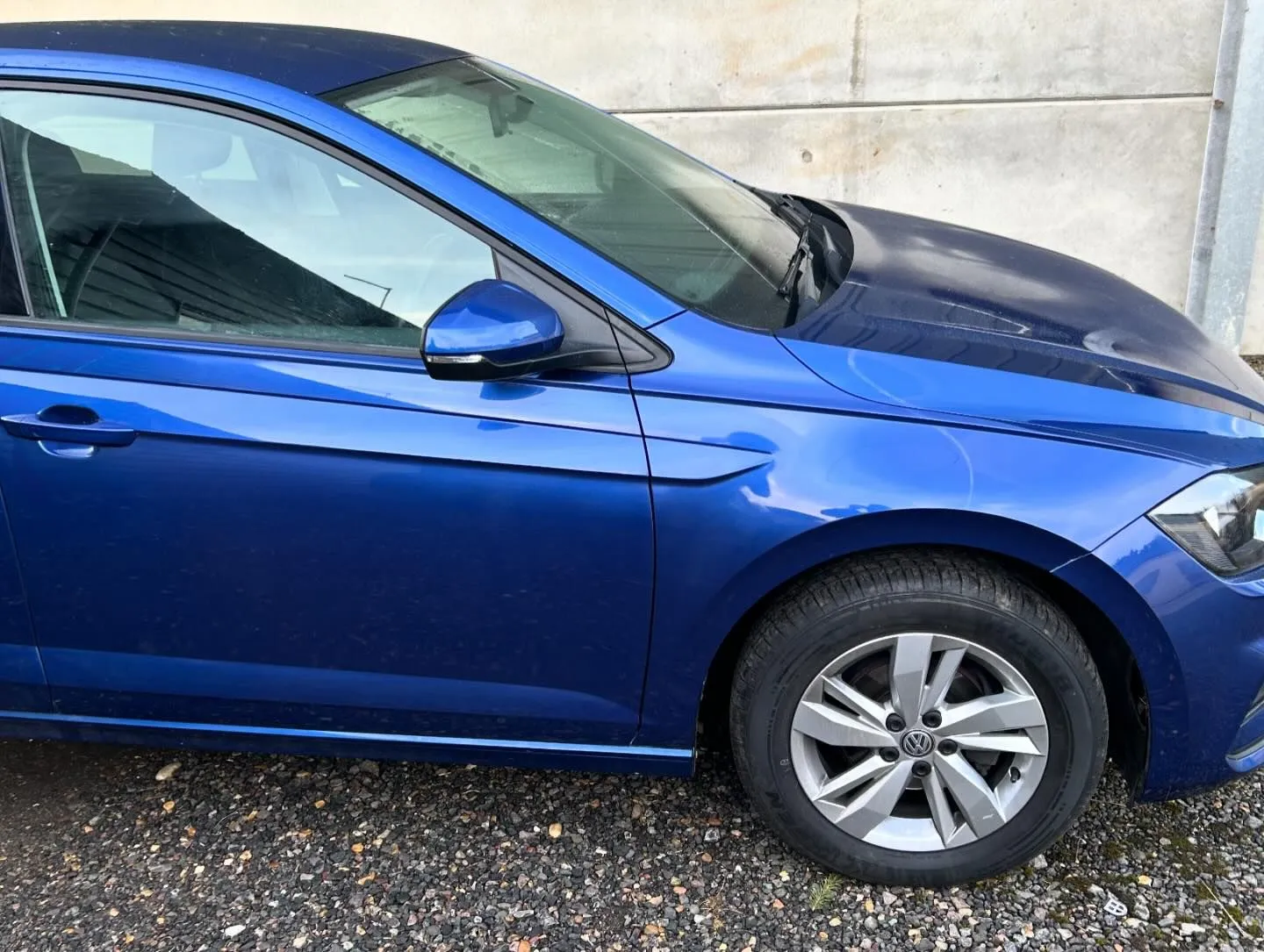 A blue car parked in front of a building.